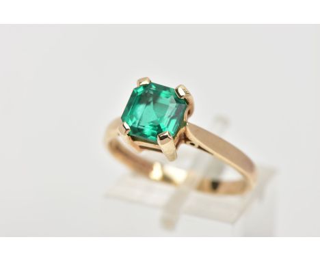 A 9CT GOLD SYNTHETIC EMERALD RING, desinged with a square cut synthetic emerald with cut off corners, four claw set, tapered 