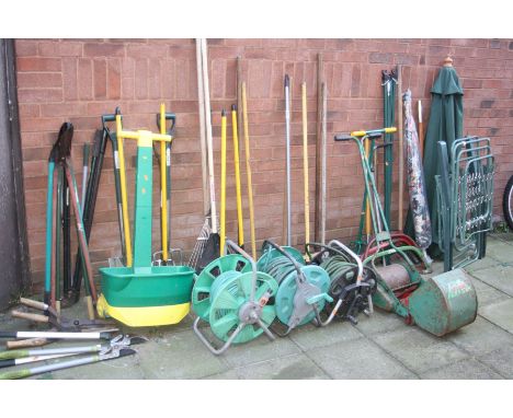 A QUANTITY OF GARDEN TOOLS to include rakes, forks, spades etc together with three hose reels, a Webb push along scarifier, p