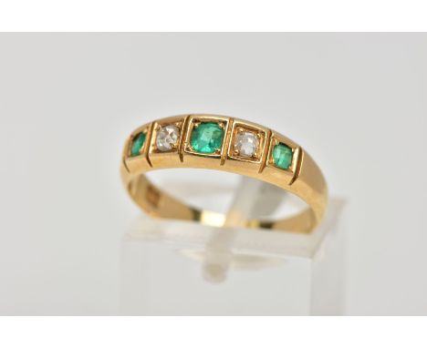 A YELLOW METAL EMERALD AND DIAMOND HALF ETERNITY RING, designed with a row of three cushion cut emeralds interspaced with two