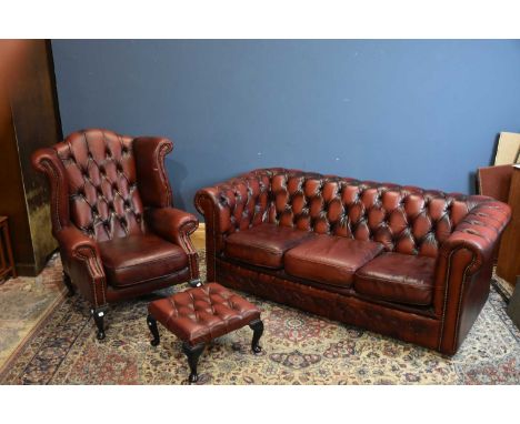 A modern Chesterfield red leather three seater sofa, length 180cm, a matching wingback armchair and footstool (3).