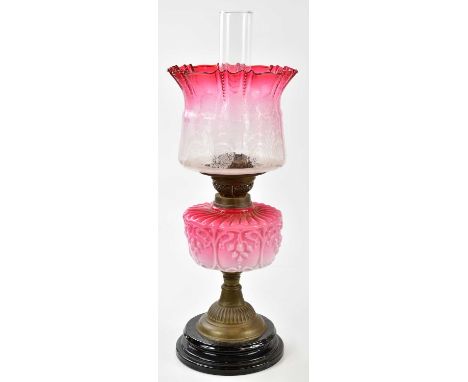 A late Victorian oil lamp, the cranberry and clear glass shade with wavy rim and frosted decoration, with the moulded cranber