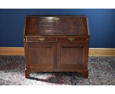 A Georgian oak bureau, the fall front with applied ornate brass escutcheon enclosing pigeon holes and assorted drawers above 