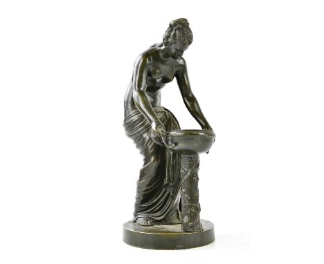 A late 19th century bronze figure representing a scantily clad classical figure kneeling lifting a twin handled bowl, height 
