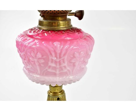 A late Victorian oil lamp, the cranberry and clear glass shade with etched decoration and wavy rim above the moulded glass re