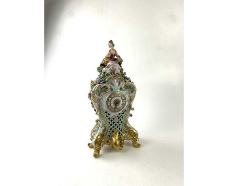 A Naples porcelain early 20th century figural mantel clock representing a maiden seated holding a basket beside a lamb, with 
