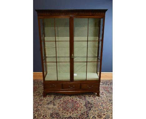 An early 20th century mahogany display cabinet, with moulded cornice above a pair of glazed doors, above three base drawers, 