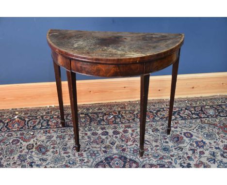 An Edwardian mahogany demi-lune card table, with hinged top on tapered legs, height 73.5cm.