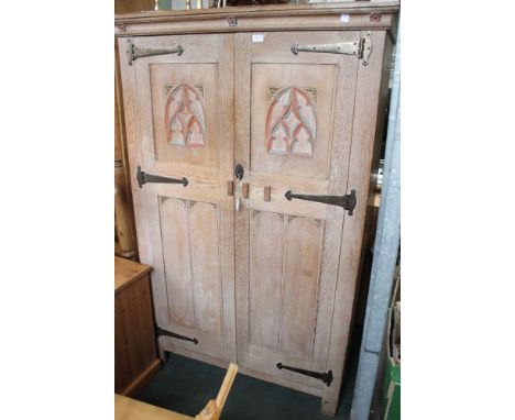 A limed oak two door wardrobe, with gothic carving