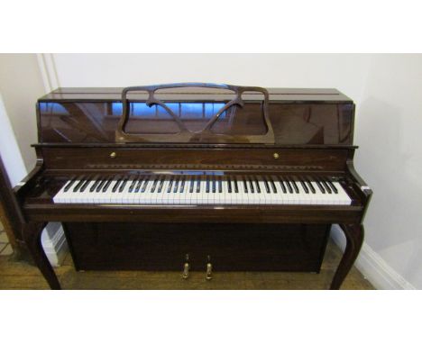 Danemann  (c1982) An upright piano in a bright mahogany modern style case with cabriole supports.