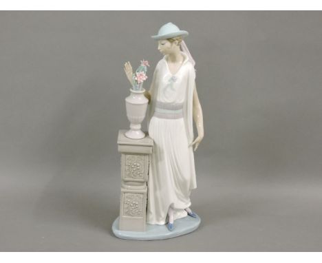 A Lladro figure, of a lady by a pedestal with a vase of flowers, 34cm