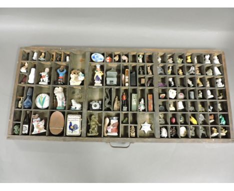 A wooden print tray with contents, including china ornaments, metal items, hardstone seals, miniature camera, glass animals, 