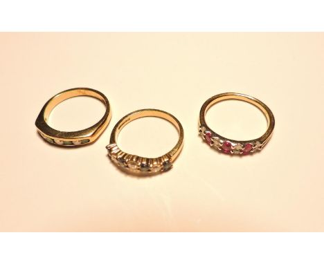 A 9ct gold ruby and diamond half hoop ring, a 9ct gold emerald and diamond channel set half hoop ring, and a 9ct gold sapphir