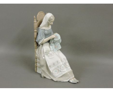 A Lladro figure, of a girl seated in a chair sewing a tapestry, 28cm