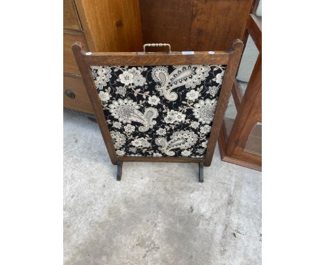AN EDWARDIAN OAK FRAMED FIRESCREEN WITH BRASS CARRYING HANDLE