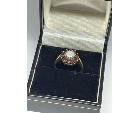 A 9 CARAT YELLOW GOLD RING WITH CENTRE OPAL SURROUNDED BY GARNETS IN A FLOWER DESIGN SIZE M IN A PRESENTATION BOX