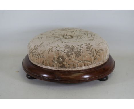 **Victorian Circular Wooden Footstool with Floral Upholstery**  Victorian-era footstool featuring a circular wooden base with