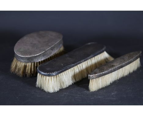 ### Set of Three Silver-Backed BrushesA collection of three vintage silver-backed brushes, including one British hallmarked p