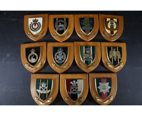 Collection of British Regimental Wall PlaquesEleven heraldic wooden shield plaques featuring emblematic crests of various Bri