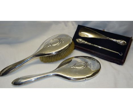 A silver handed Button Hook, glove button hook and shoe horn, together with a silver back hand mirror and brush.