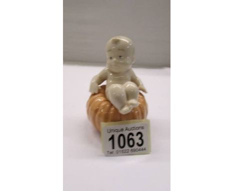 A NAO figure of a baby sat on a pumpkin.