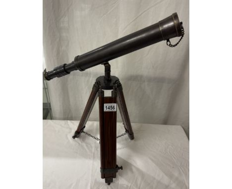 A patinated brass telescope on tripod base. Length 43cm