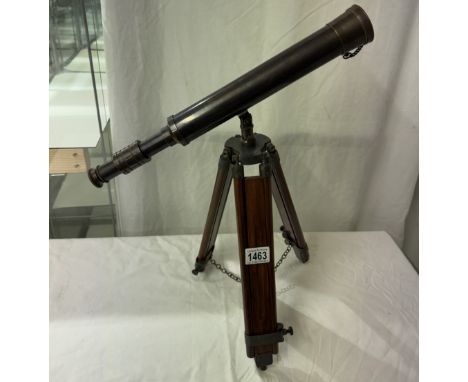 A patinated brass telescope on tripod base. Length 43cm
