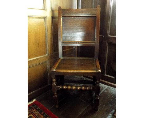 A William III oak back stool, the single panel back over a boarded seat, on baluster and block front supports, united by bobb