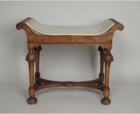 A 1920s William and Mary style walnut dressing stool, the dished seat on four inverted cup and cover columns, united by an X-