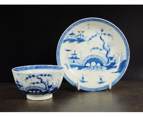 A Caughley tea bowl and saucer, circa 1785, painted in underglaze blue with the Bridge and Windmill pattern, between an assoc