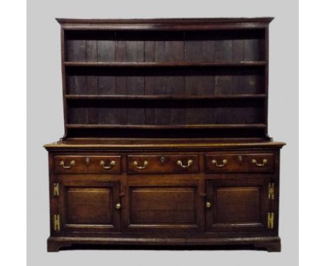 A George III oak high dresser, the boarded three shelf delft rack over three short frieze drawers to the enclosed base fitted