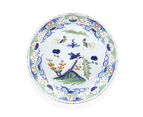 An English delftware plate, circa 1730Probably Bristol, of 'pancake' shape, painted in blue, red and green with a pair of liv