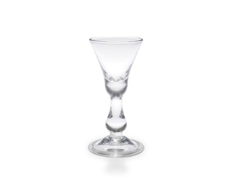 A heavy baluster wine glass, circa 1710-20The slightly waisted bell bowl with a solid base, over a long solid true baluster o