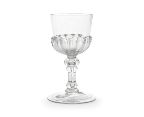 A rare baluster mead or champagne glass, early 18th centuryThe distinctive 'U' shaped bowl moulded with a ring of fourteen ev