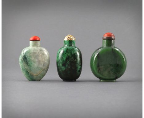 † λ THREE CHINESE JADE SNUFF BOTTLES, 19TH CENTURY Two in jadeite, the third nephrite, one disc-shaped, another carved in rel