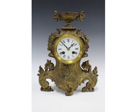 A French brass cased mantle clock, with an urn surmount over a circular dial within a rococo style case, 34cm 