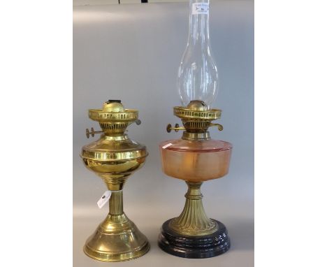 Early 20th Century double oil burner lamp, having orange reservoir on a brass and ebonised base. Together with another early 