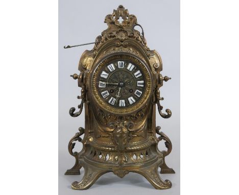 A French style brass mantel clock in scrolling Rococo case with enamel Roman numerals and eight day movement, with key and pe