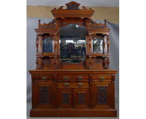 A late Victorian carved walnut mirror backed sideboard with shaped bevelled plates and turned pilasters above drawers and pan