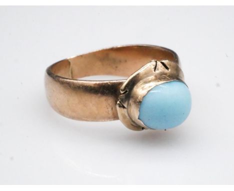 A Victorian 18 carat rose gold solitaire ring, set to centre with a pale blue glass cabochon in an engraved, rub over setting