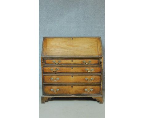 A Georgian mahogany bureau with fall front revealing fitted interior above four graduating oak crossbanded drawers on bracket