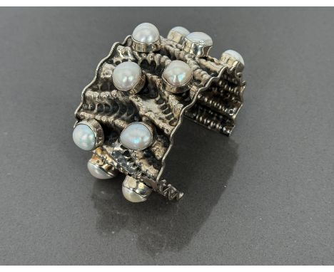 A striking sterling silver and baroque Mabe pearl cuff bangle - bark effect design with eleven large baroque pearls in collet