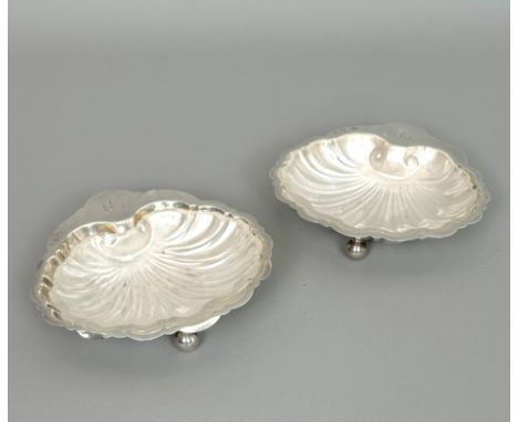 A pair of George V silver butter shells - Barker Brothers, Chester 1913, typical form with three ball feet and clear frosted 