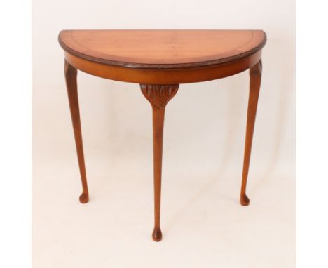A Georgian-style yew veneered demi-lune console table - with crossbanded top, carved edge and three foliate carved cabriole s
