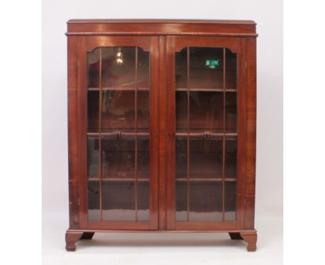 A 1930s mahogany glass-fronted bookcase - the caddy top over a pair of six pane astragal glazed door, enclosing an interior w