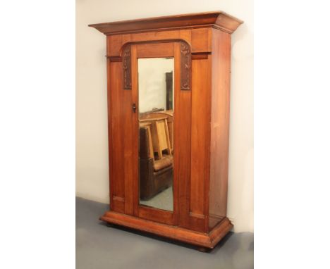 An early 20th century Arts &amp; Crafts style walnut wardrobe - the flared, ogee cornice over a central bevelled mirrored doo