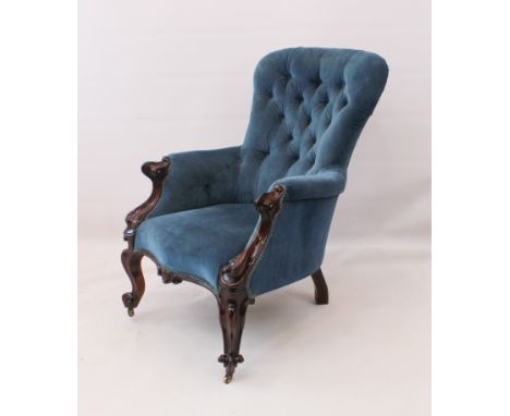 A Victorian walnut armchair - in button-back blue velour upholstery, with scroll carved arms, serpentine seat and scroll carv