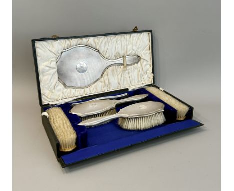 A cased George V six-piece silver dressing table set - Synyer &amp; Beddoes, Birmingham 1924, of serpentine form with engine 
