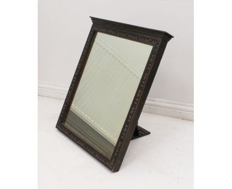 An early 20th century carved oak easel back mirror - the rectangular plate within an egg-and-dart carved frame, below a mould