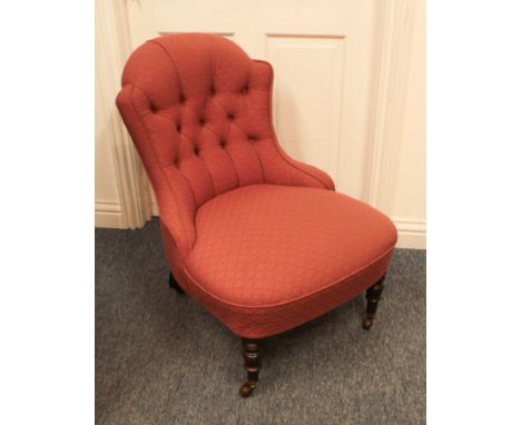 A late-19th century button back low ladies chair - the shaped spoon back and seat upholstered in dusky pink, on turned front 