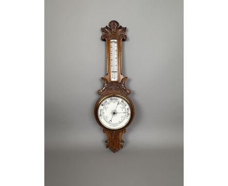 A carved oak aneroid barometer - early 20th century, the case carved with foliage, holding a 7&frac12;in white china dial and